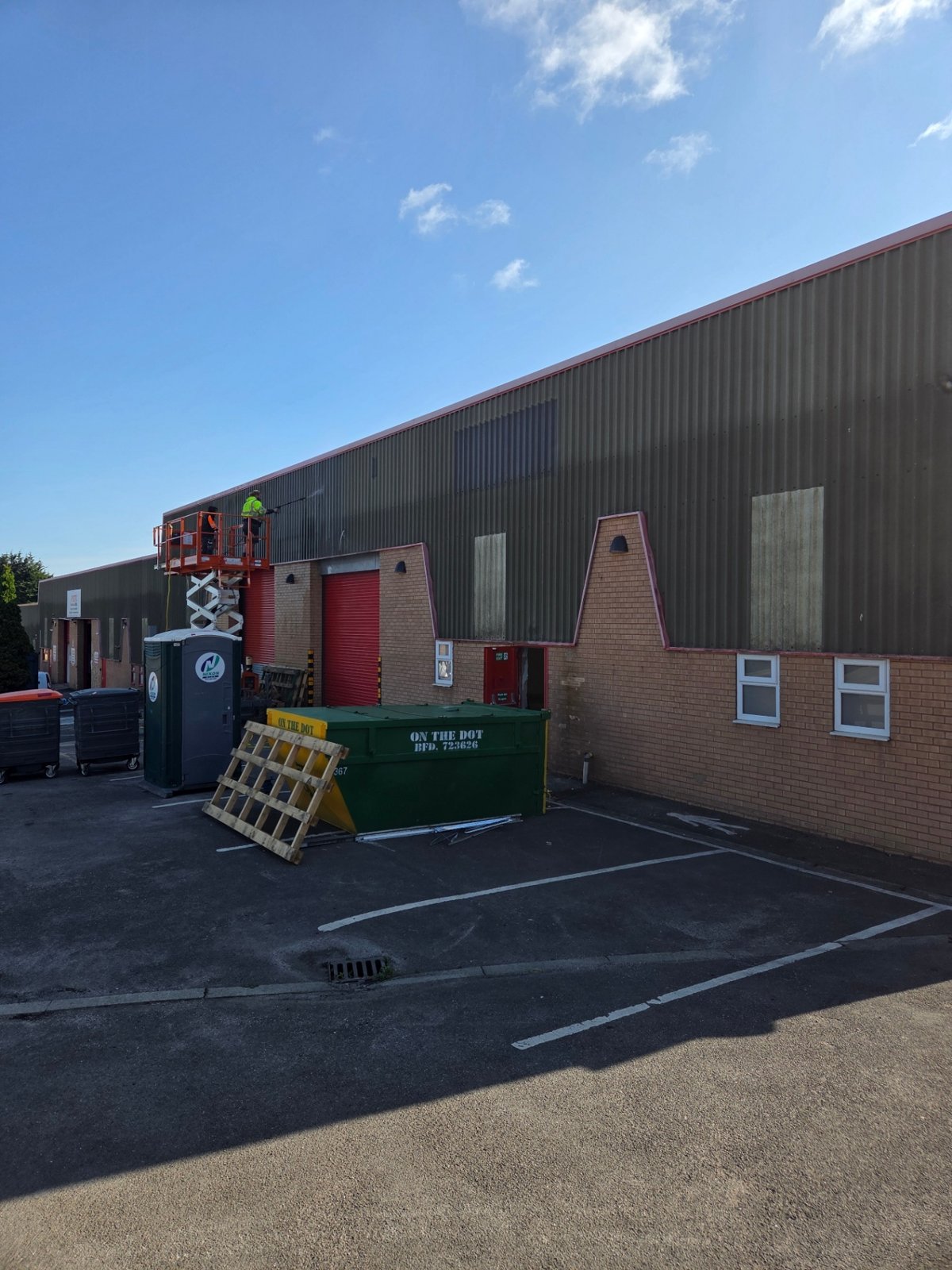 Company-supplied photograph: Original cladding and red roller shutters with scissor-lift access