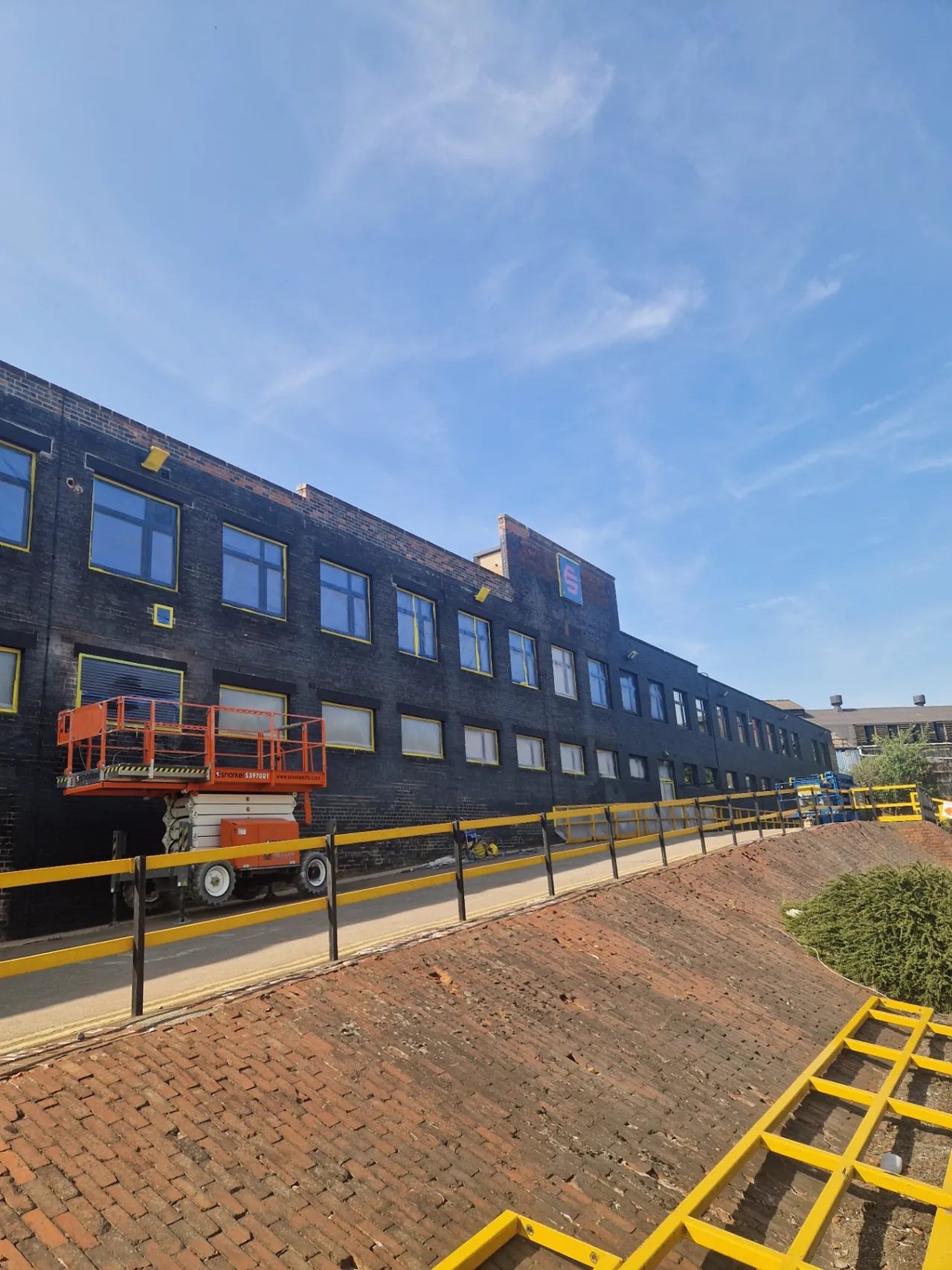 Company-supplied photograph: Masked windows and scissor lift along the office-block elevation