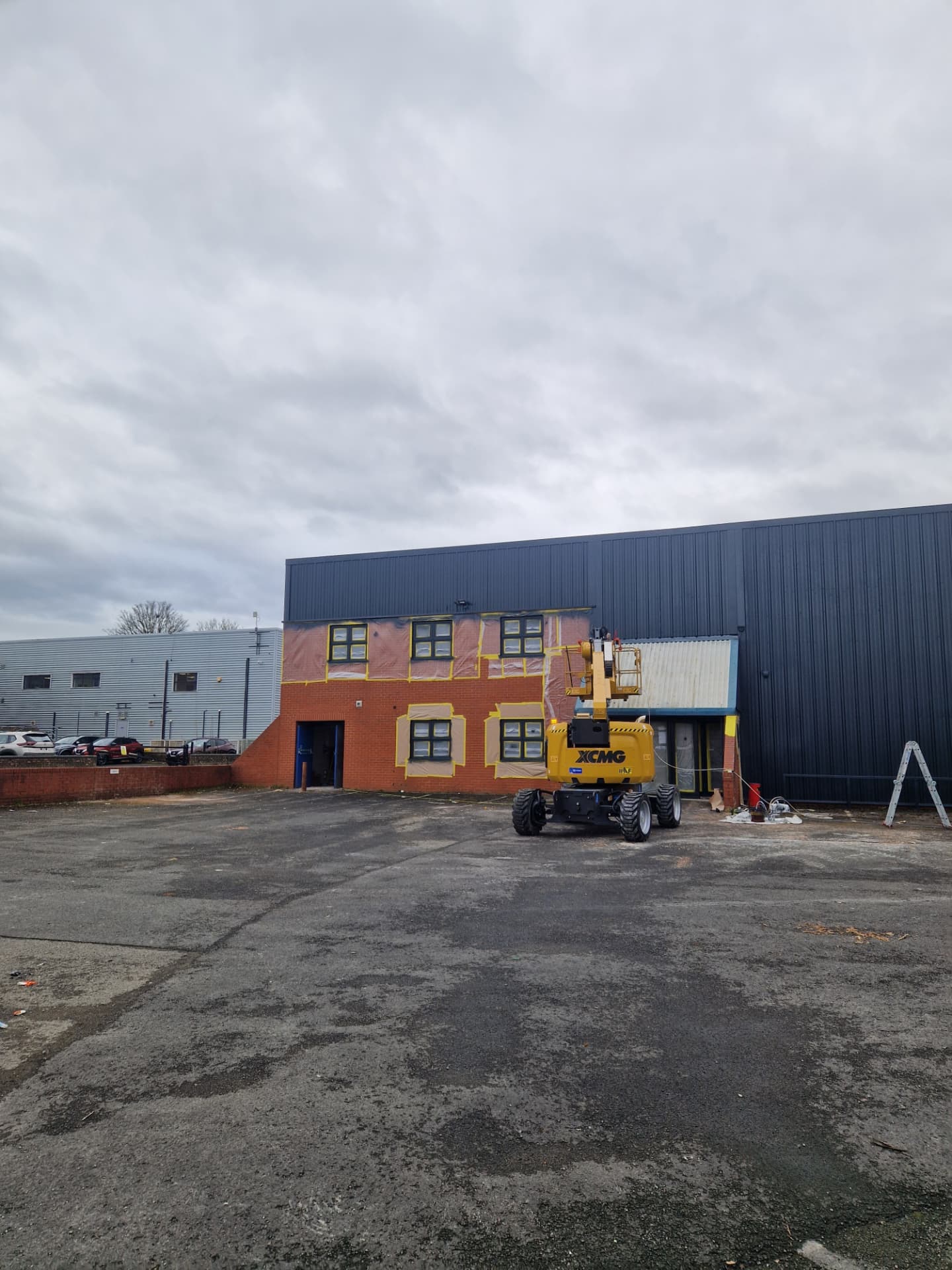 Company-supplied photograph of the X Martial Arts frontage during respraying, with brickwork and windows masked and a boom lift on site