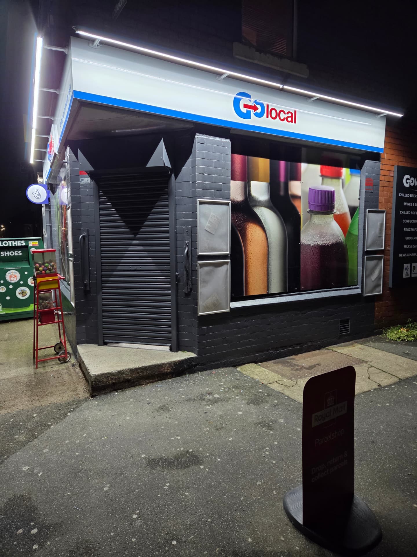 Company-supplied photograph of a resprayed convenience store frontage at night with roller shutters closed