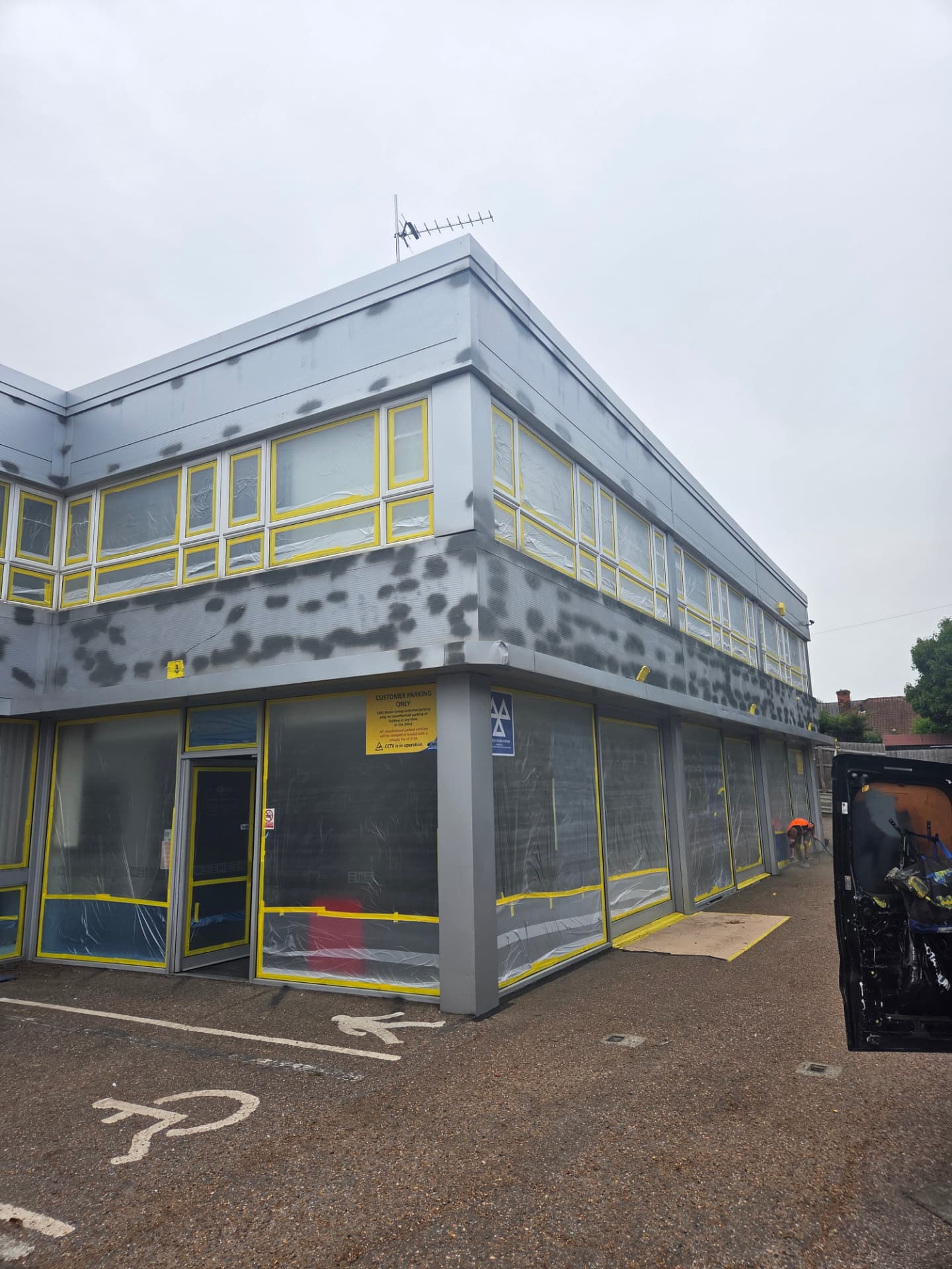Company-supplied photograph of the Ford showroom with spot-primed cladding repairs and masked windows and doors