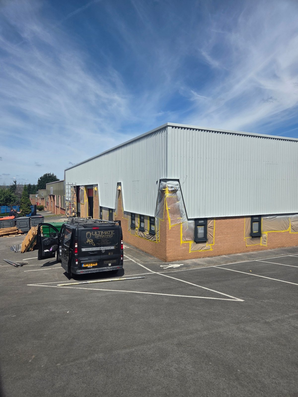Company-supplied photograph: Light grey cladding around the Bradford building corner with glazing masked and company van on site