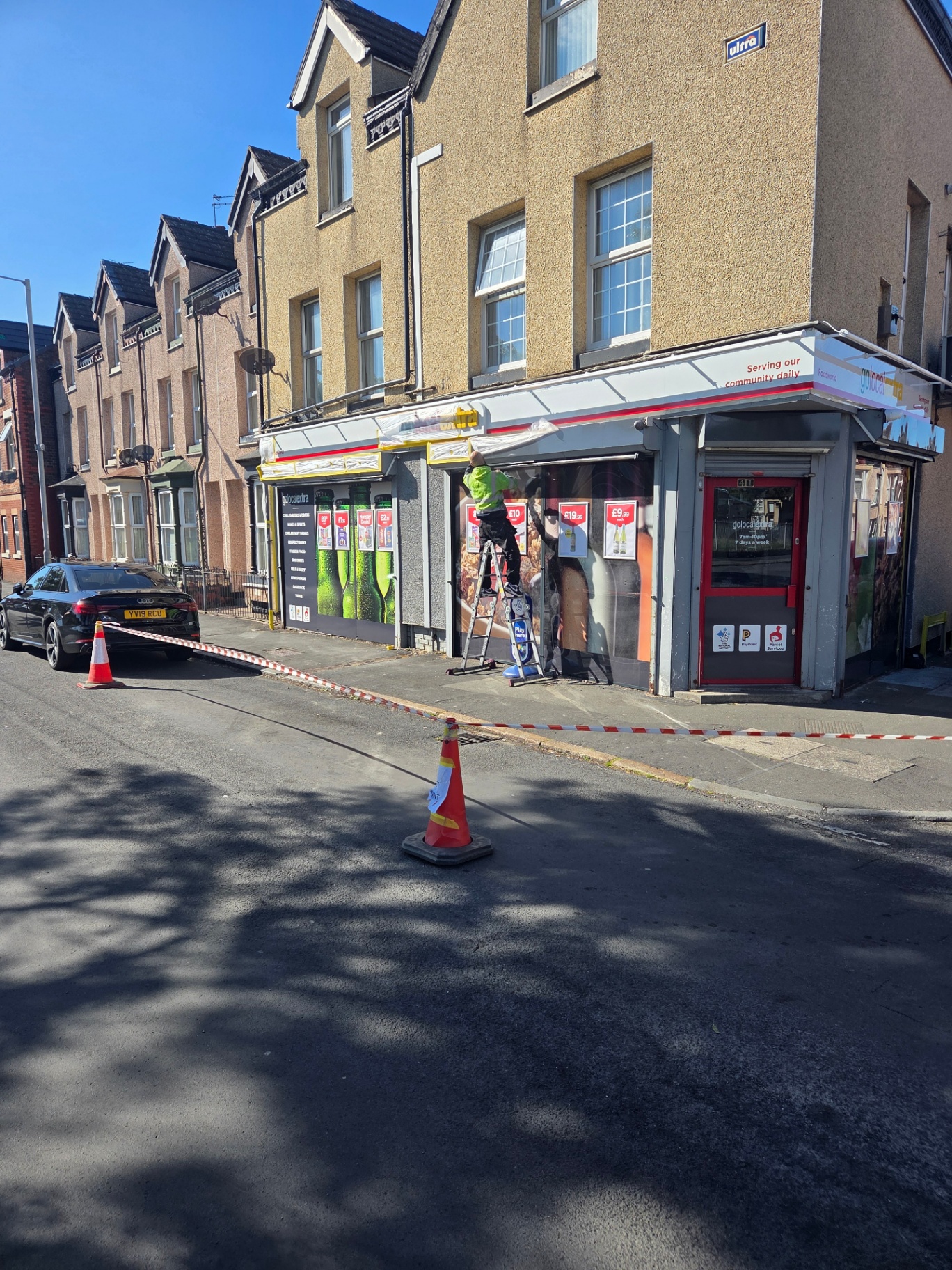 Company-supplied photograph of a Go Local Extra store entrance being sprayed on site, with the shopfront masked and the street barriered