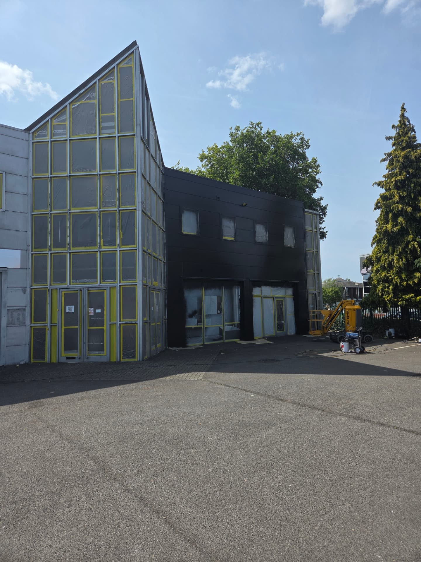 Company-supplied photograph of the showroom atrium glazing masked with yellow protection during preparation