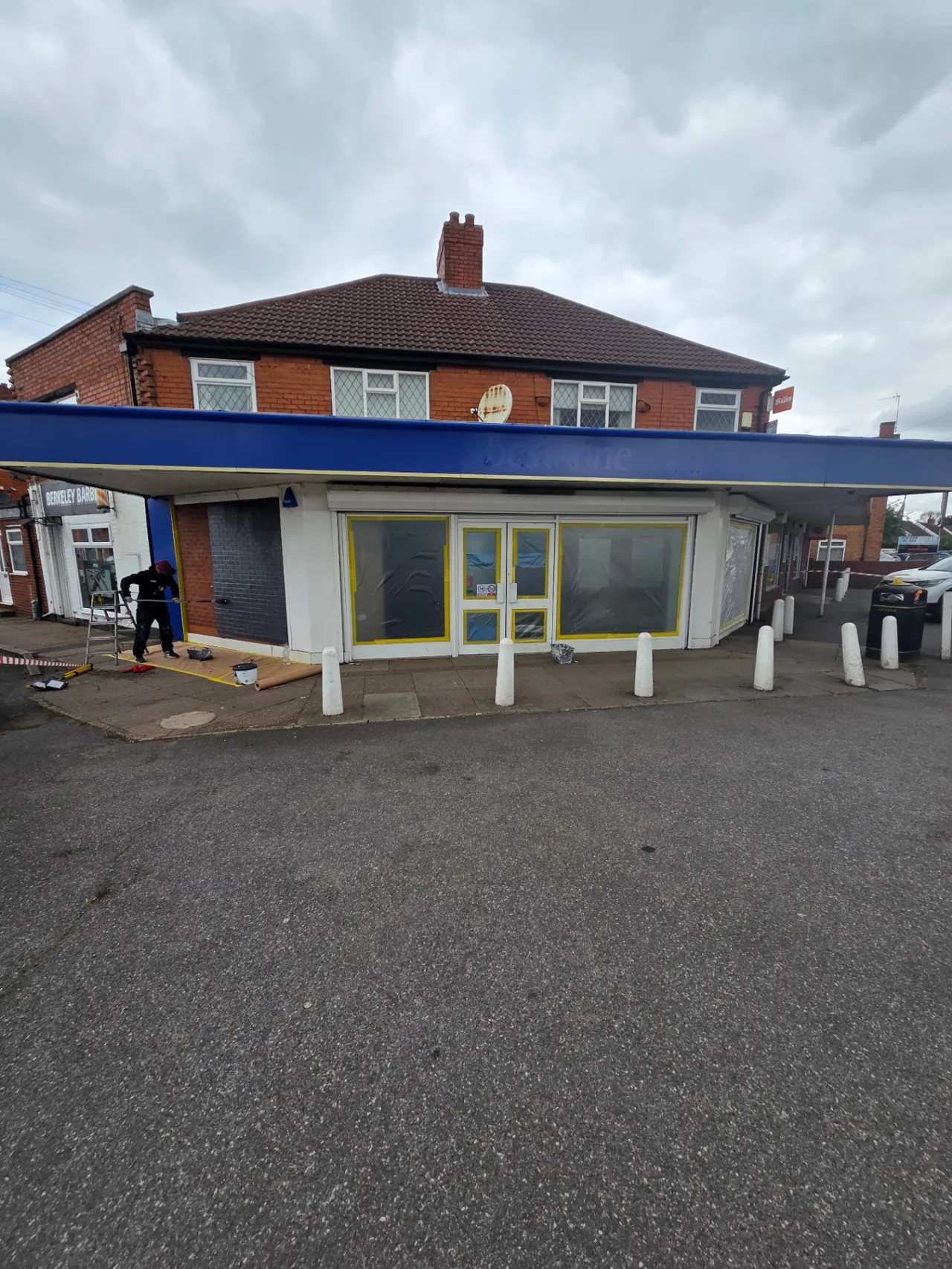 Company-supplied photograph: Company-supplied photograph of the best-one store frontage before respraying, with the original white framing and canopy masked