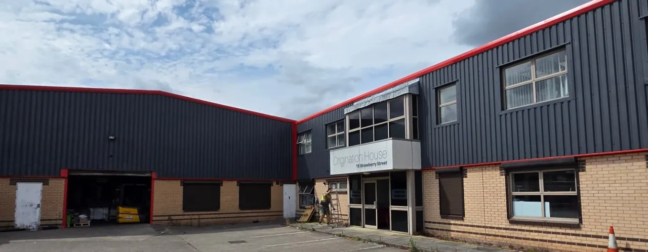 Company-supplied photograph of the resprayed Hull building front elevation with RAL 7024 cladding, traffic red trims and the main entrance