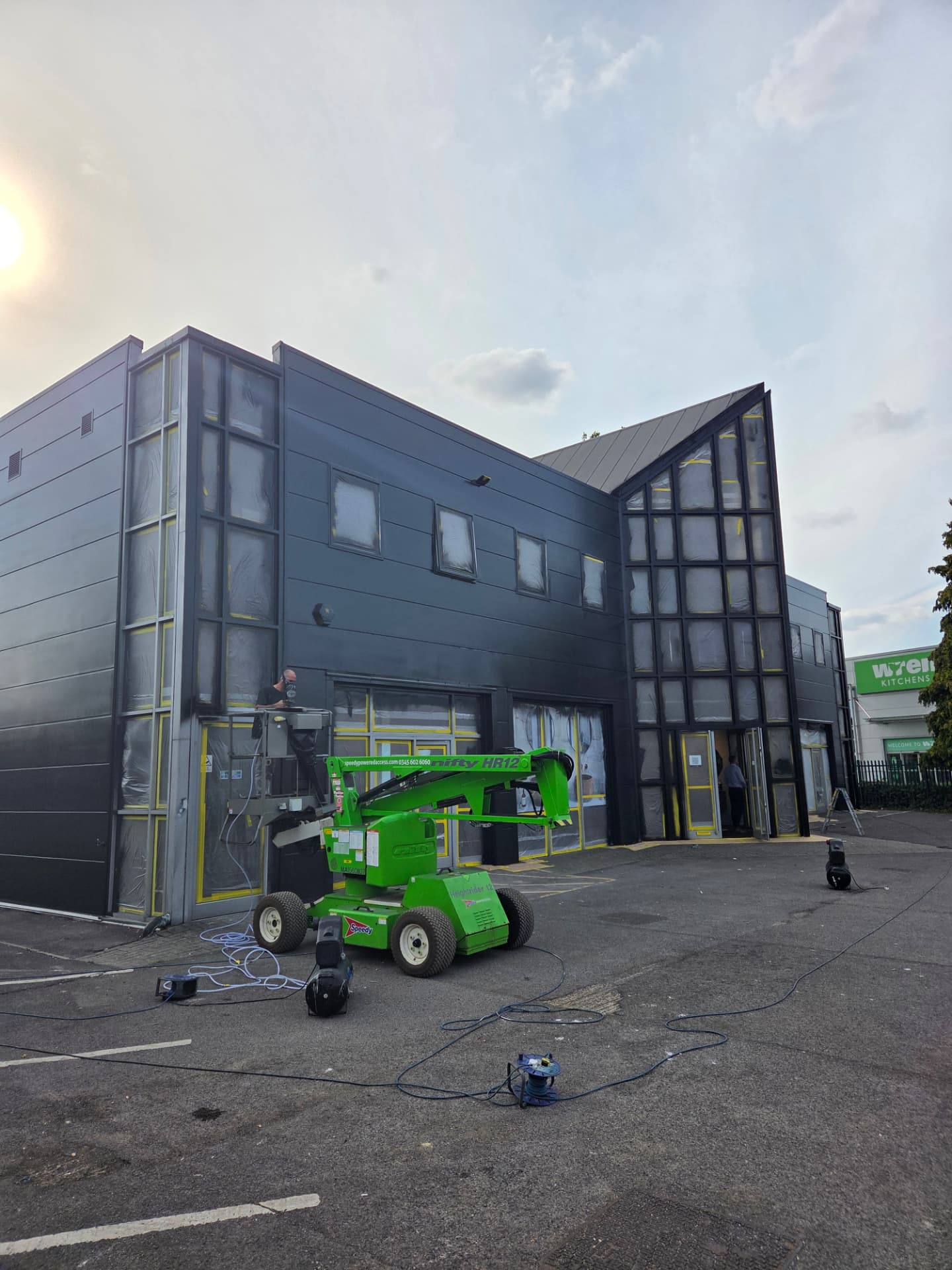 Company-supplied photograph of the showroom being sprayed from a green access machine with masking in place
