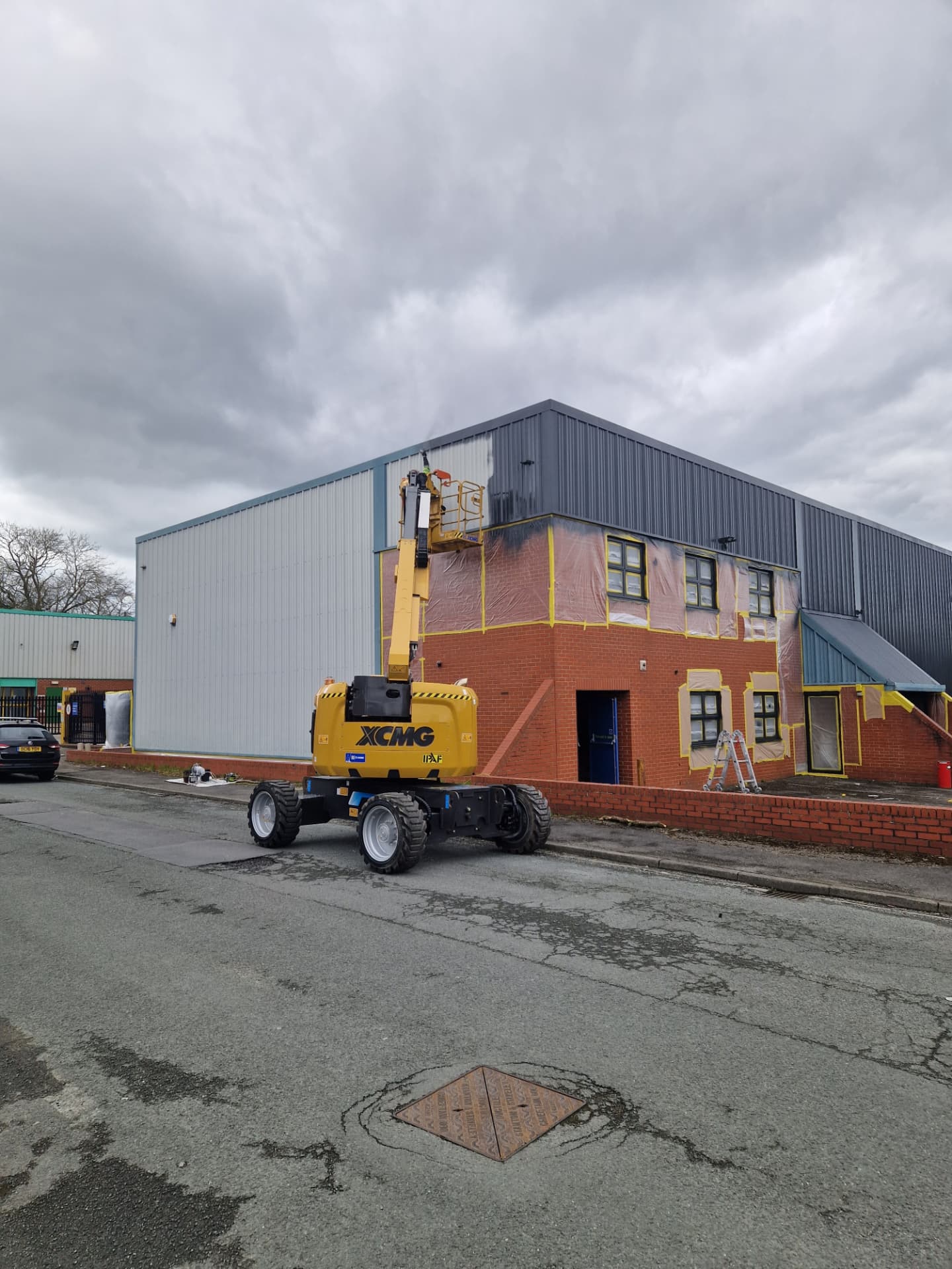 Company-supplied photograph of the X Martial Arts corner elevation during the works, with masking and a boom lift in place