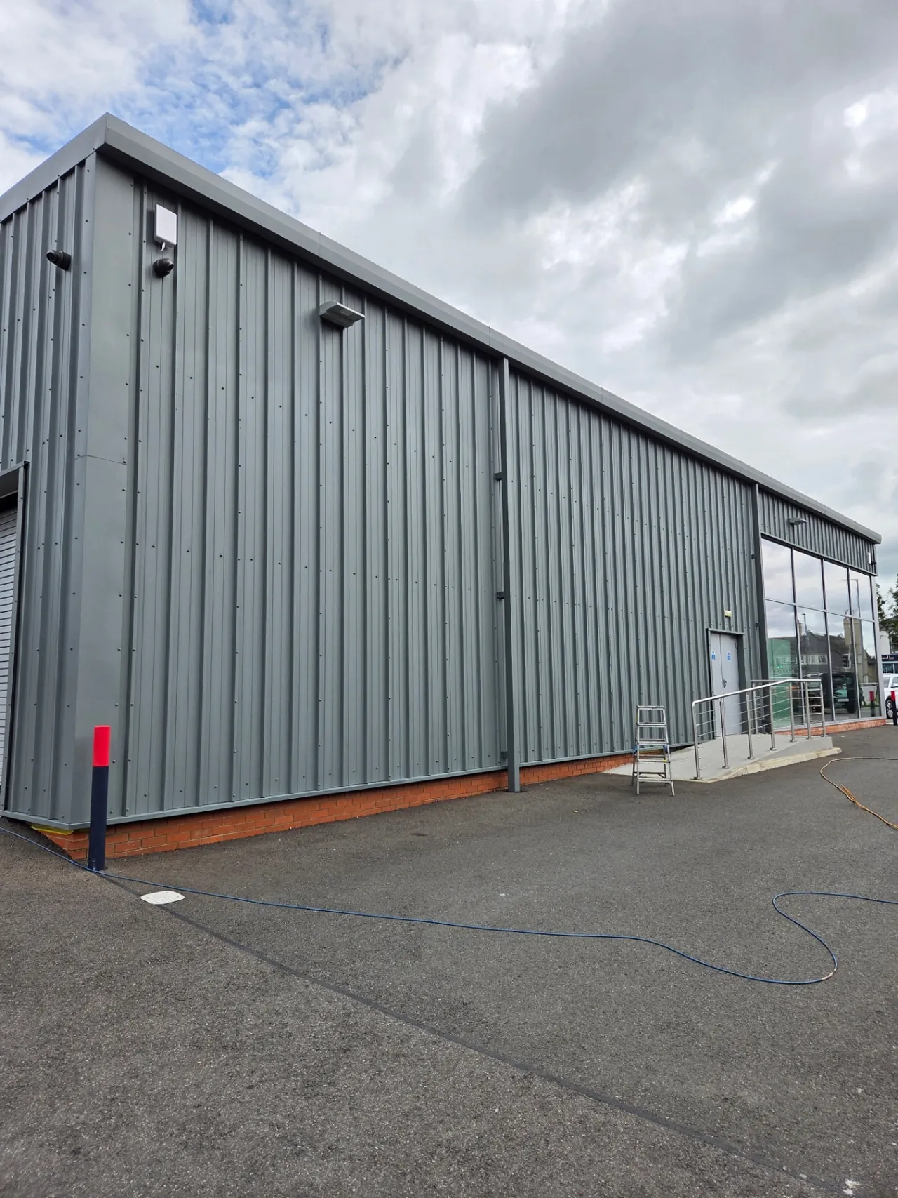 Company-supplied photograph: Completed RAL 7005 mouse grey cladding along the showroom side elevation