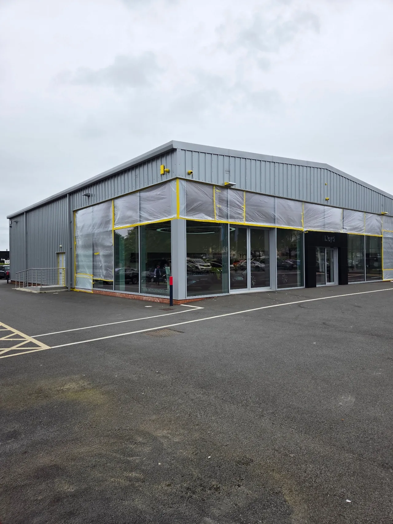 Company-supplied photograph: Showroom glazing masked with protective sheeting before cladding respraying