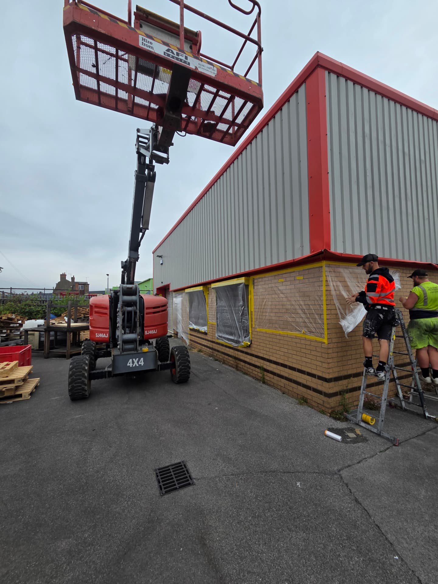 Company-supplied Hull process photograph showing window and brickwork masking beside a boom lift
